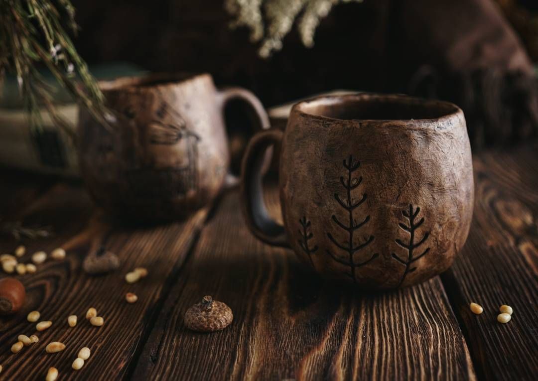 Warm ceramic mug with herbal tea beside pine sprigs on a linen surface